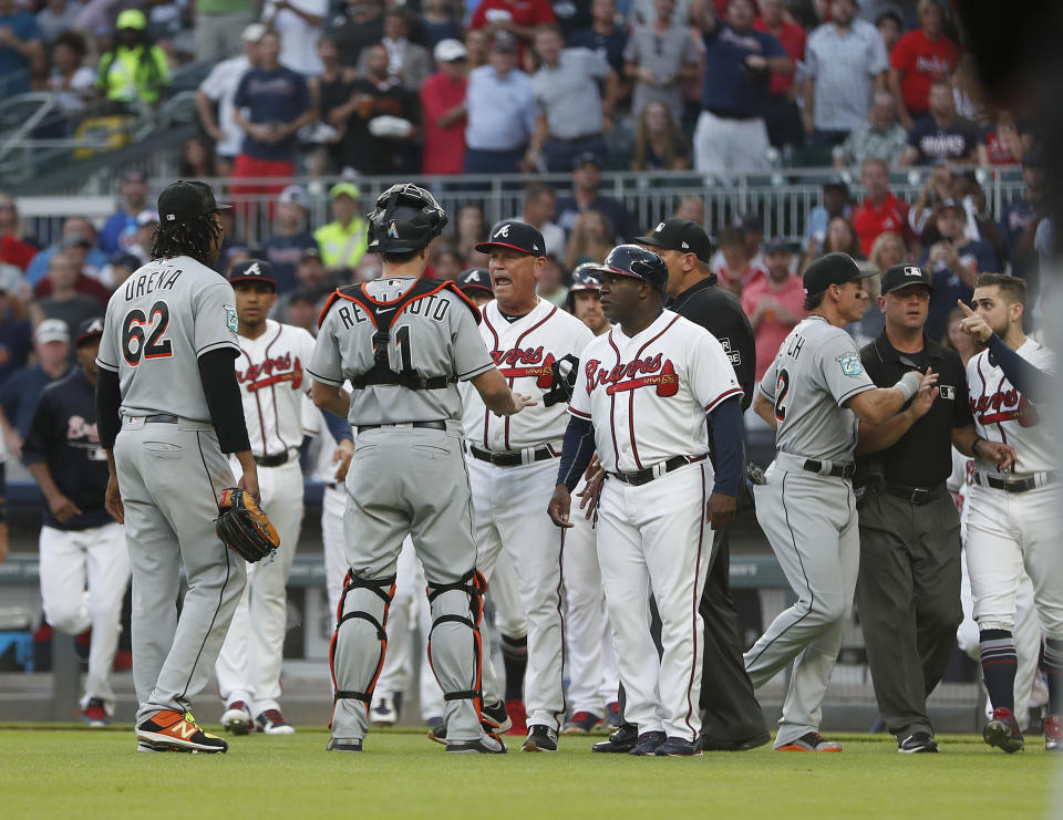 Miami Marlins catcher J.T. Realmuto (11) stands between pitcher Jose Urena (62) and Atlanta Braves manager Brian Snitker (43) as the dugouts empty after Urena hit Braves' Ronald Acuna Jr. with a pitch during the first inning of a baseball game Wednesday, Aug. 15, 2018m in Atlanta. Marlins' Derek Dietrich (32) and Braves' Ender Inciarte argue at right. (AP Photo/John Bazemore)