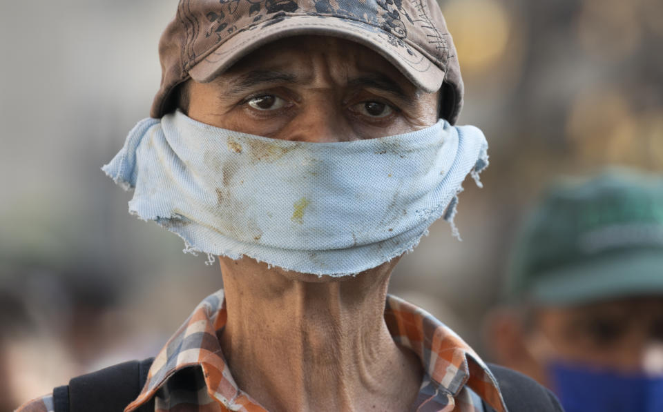 A man wears a piece of cloth as a face mask amid the spread of the new coronavirus at a street market in Caracas, Venezuela, Friday, April 10, 2020. (AP Photo/Ariana Cubillos)