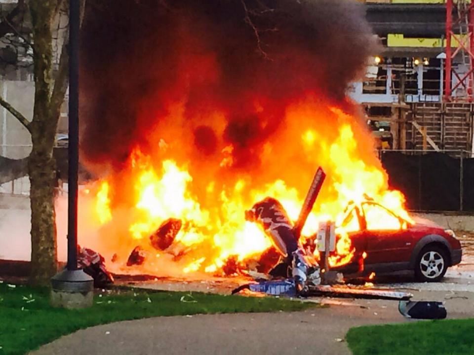 Fotografía provista por la televisora KOMO-TV, de un automóvil incendiándose tras la caída de un helicóptero fuera de los propios estudios de KOMO-TV cerca de la emblemática torre Space Needle ("Aguja Espacial") en Seattle, Washington, el martes 18 de marzo de 2014. (Foto AP/KOMO-TV, Kelly Koopmans) CREDITO OBLIGATORIO: KOMO-TV