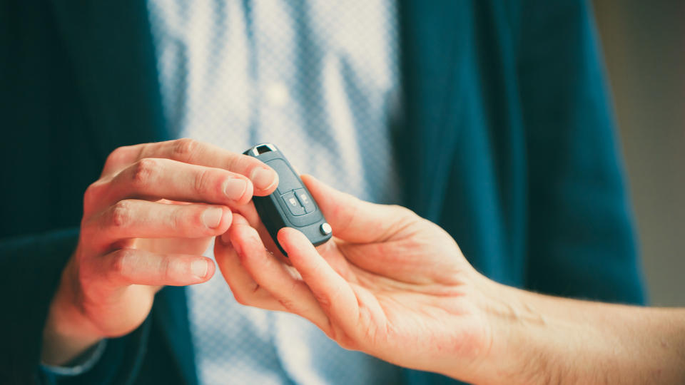 man handing car key to another person