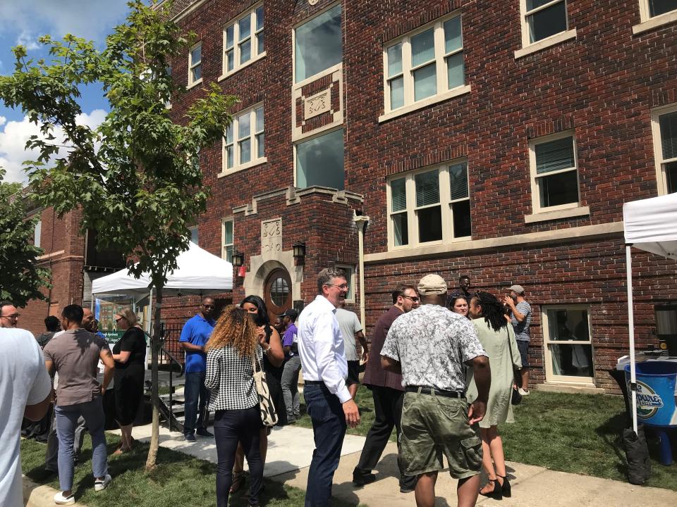 A crowd of officials connected with the renovation of a historic apartment building in Detroit's Jefferson Chalmers area mixes Thursday with neighbors over coffee and doughnuts after watching the ribbon-cutting. In center in white shirt is Josh Elling, CEO of Jefferson East Inc., the nonprofit growth corporation that is spurring redevelopment of the Jefferson Avenue corridor. (Photo: Bill Laitner)