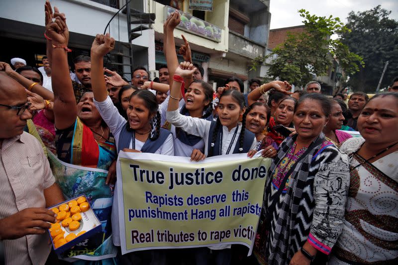 La gente grita consignas mientras celebran después de que la policía mató a tiros a cuatro hombres sospechosos de violar y matar a un veterinario de 27 años en Telangana, en Ahmedabad