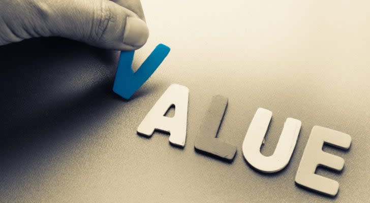 Value stocks: A hand places wooden cutouts of the letters in the word "value" on a surface.