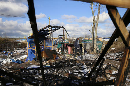 A migrant walks near the remains of burnt makeshift shelters in the shanty town called the "Jungle" in Calais, France, March 7, 2016. REUTERS/Pascal Rossignol