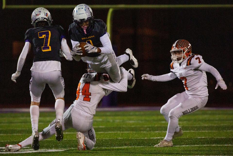Bloom-Carroll's Beau Wisecarver (1) gets tossed into the air by Heath's Mitchell McClain (84) as he goes for more yardage as Heath played Bloom-Carroll at St. Francis DeSales High School during the Division IV, Region 15 semifinal in Columbus, Ohio on November 12, 2021.