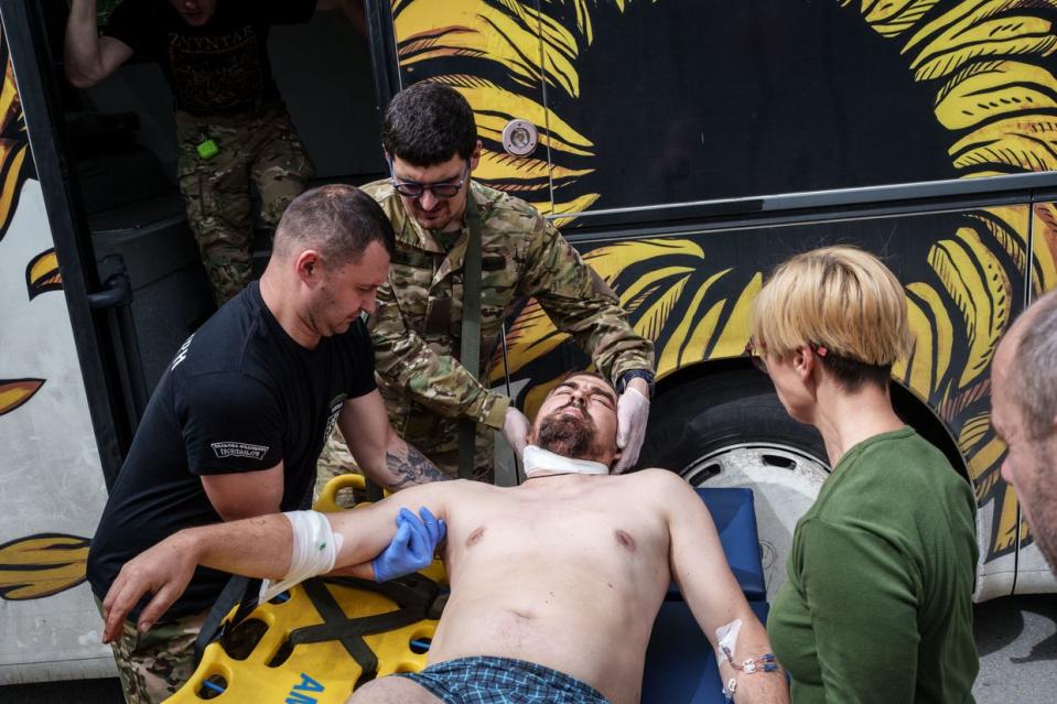 Members of the Hospitallers Medical Battalion carry a wounded soldier into the bus to evacuate him from the front line in Donetsk Oblast to a hospital in Dnipro city on April 25, 2024. (Serhii Korovayny/The Kyiv Independent)