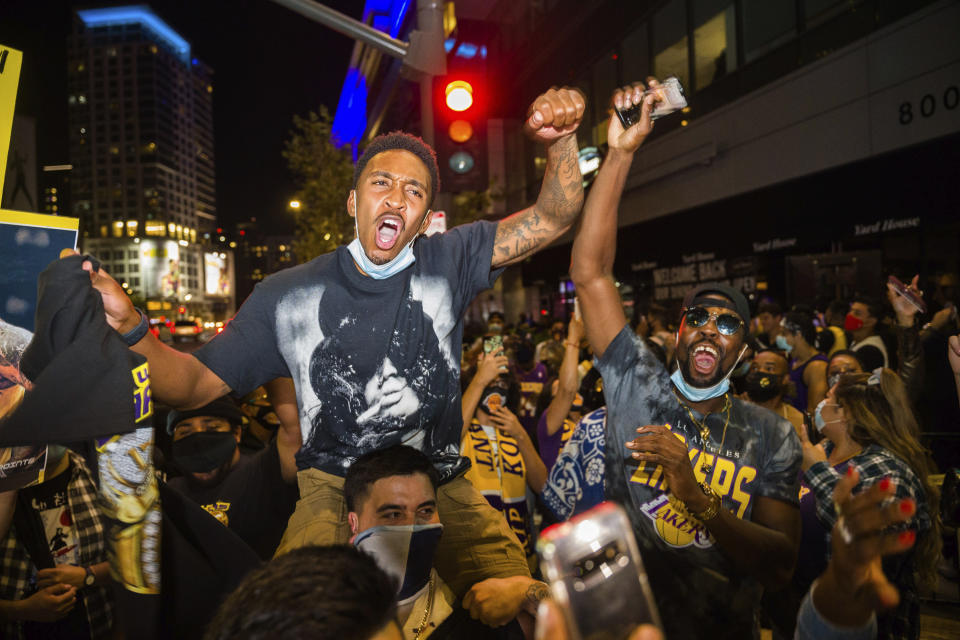 FILE - In this Oct. 11, 2020, file photo, fans in Los Angeles celebrate after the Los Angeles Lakers defeated the Miami Heat in Game 6 of basketball's NBA Finals to win the championship. A backlog in coronavirus testing results hid a recent rise in infections in Los Angeles County, the county's top health official said Monday, Oct. 26, 2020, warning that fans gathering to watch recent championship sporting events may have increased the spread. (AP Photo/Jintak Han, File)