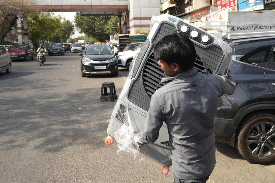 Un hombre lleva un aparato de refrigeración a su casa ante el aumento de las temperaturas en Nueva Delhi, India, el 27 de mayo de 2024. (AP Foto/Manish Swarup)