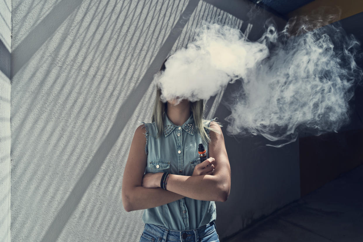 Young woman with her head in a cloud of vapor smoke