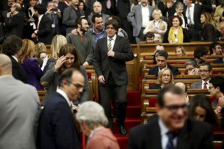 Incoming Catalan President Carles Puigdemont (C) adjusts his jacket during the investiture session at the Catalunya Parliament in Barcelona, Spain, January 10, 2016. REUTERS/Albert Gea