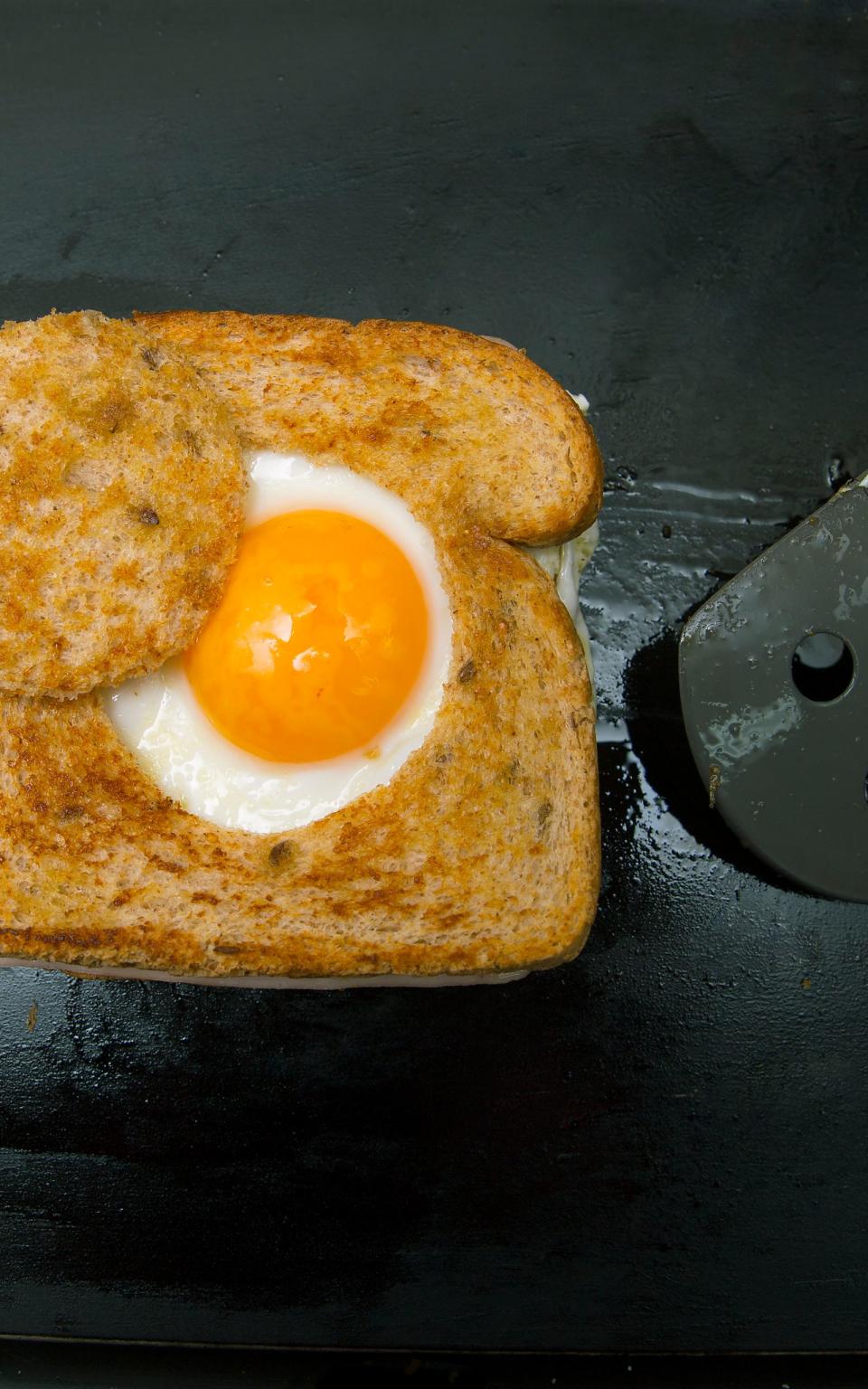 Nicht nur ein Gaumenschmaus, sondern auch schön anzuschauen sind Spiegeleier im Toast-Loch. Für dieses Rezept werden Toast-Scheiben mithilfe eines Glases kreisrund ausgestochen, sodass ein dicker Brot-Rand übrig bleibt. Im nächsten Schritt wird das Brot mit Speck in der Pfanne angebraten und schließlich die Eier in das Loch gegossen. (Bild: iStock/kemirada)