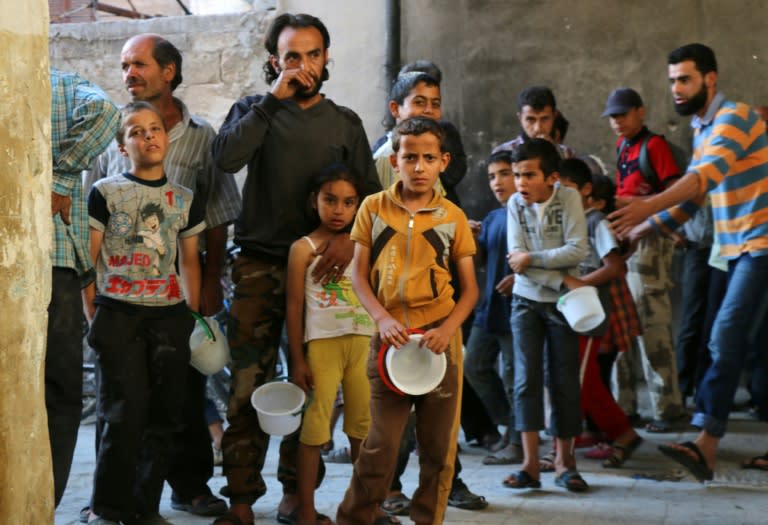 Syrians line-up to receive meals distributed by the "Syria charity" NGO to impoverished families during the Muslim holy fasting month of Ramadan in a rebel-held neighbourhood of the northern city Aleppo