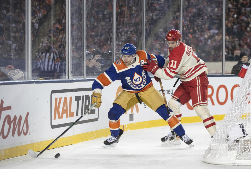 Calgary Flames' Mikael Backlund (11) and Edmonton Oilers' Connor McDavid (97) battle for the puck during third-period NHL Heritage Classic outdoor hockey game action in Edmonton, Alberta, Sunday, Oct. 29, 2023. (Jason Franson/The Canadian Press via AP)