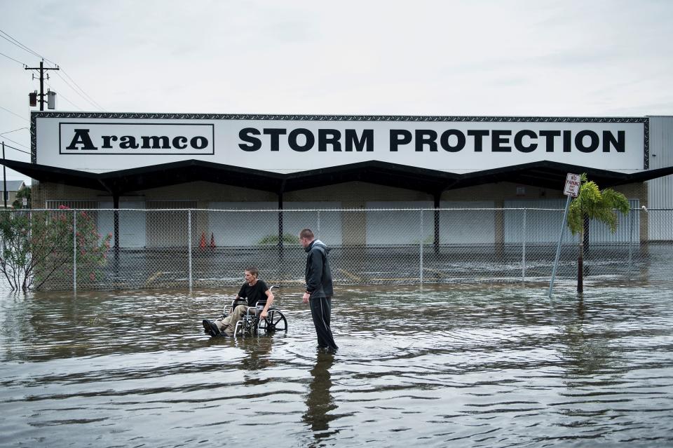 Brad Matheney helps a man in a wheelchair navigate a flooded street in Galveston, Texas, on Saturday. (Photo: BRENDAN SMIALOWSKI/AFP/Getty Images)