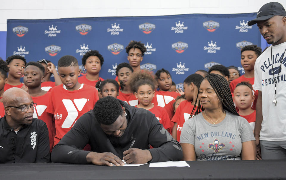 New Orleans Pelicans forward Zion Williamson, center, signs his contract extension surrounded by his family and children attending camp at the Dryades YMCA in New Orleans, Wednesday, July 6, 2022. (Max Becherer/The Times-Picayune/The New Orleans Advocate via AP)