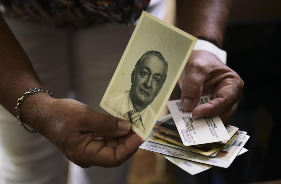 FILE - In this June 7, 2018 file photo, Nerybelle Perez holds a picture of her father, World War II veteran Efrain Perez, who died inside an ambulance after being turned away from the largest public hospital when it had no electricity or water, days after Hurricane Maria hit Guaynabo, Puerto Rico. Researchers from George Washington University hired by Puerto Rico's government estimated in Aug. 2018 that 2,975 people had died because of Maria in the six months after landfall, a number Puerto Rico accepted as official. (AP Photo/Carlos Giusti, File)