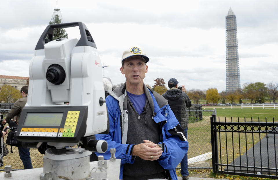 Dru Smith, Chief Geodesist of the National Geodetic Survey stands near a measurement device used to survey the height of the Washington Monument, Thursday, Nov. 7, 2013, in Washington. Surveyors are checking to make sure that the Washington Monument is still 555 feet, 5 1/8 inches tall. The survey is being conducted by the National Geodetic Survey and is the first of its kind since 1999. Surveyors can only access the peak of the monument to check the height when it's covered in scaffolding. The monument is undergoing repairs after it was damaged during a 5.8-magnitude earthquake in August 2011. (AP Photo/Susan Walsh)