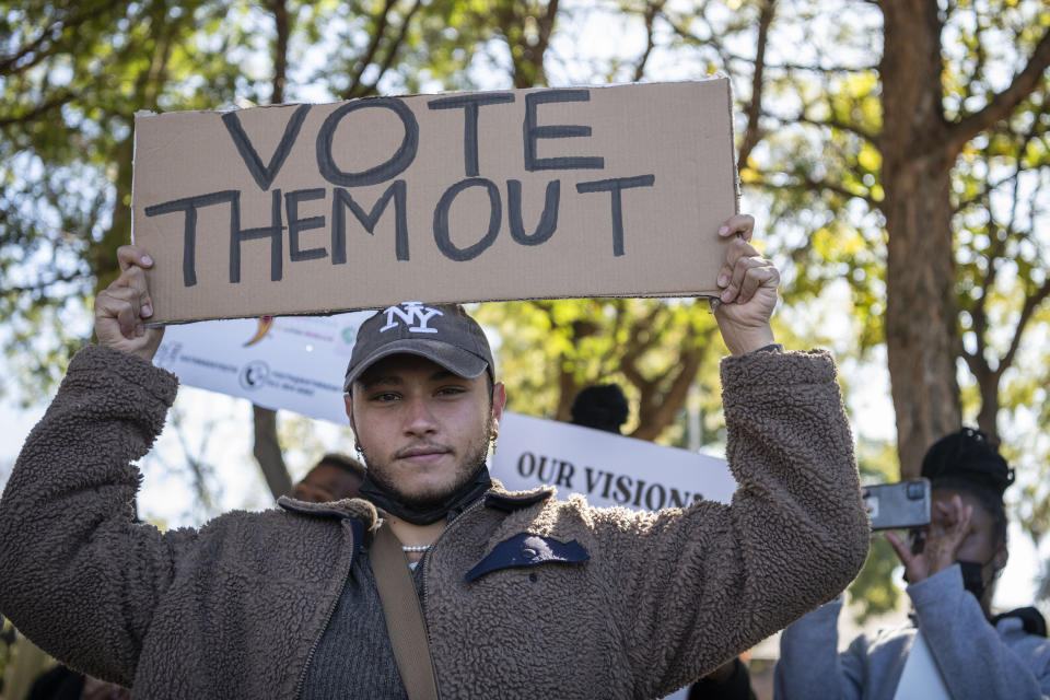 a man holds a sign saying "vote them out"