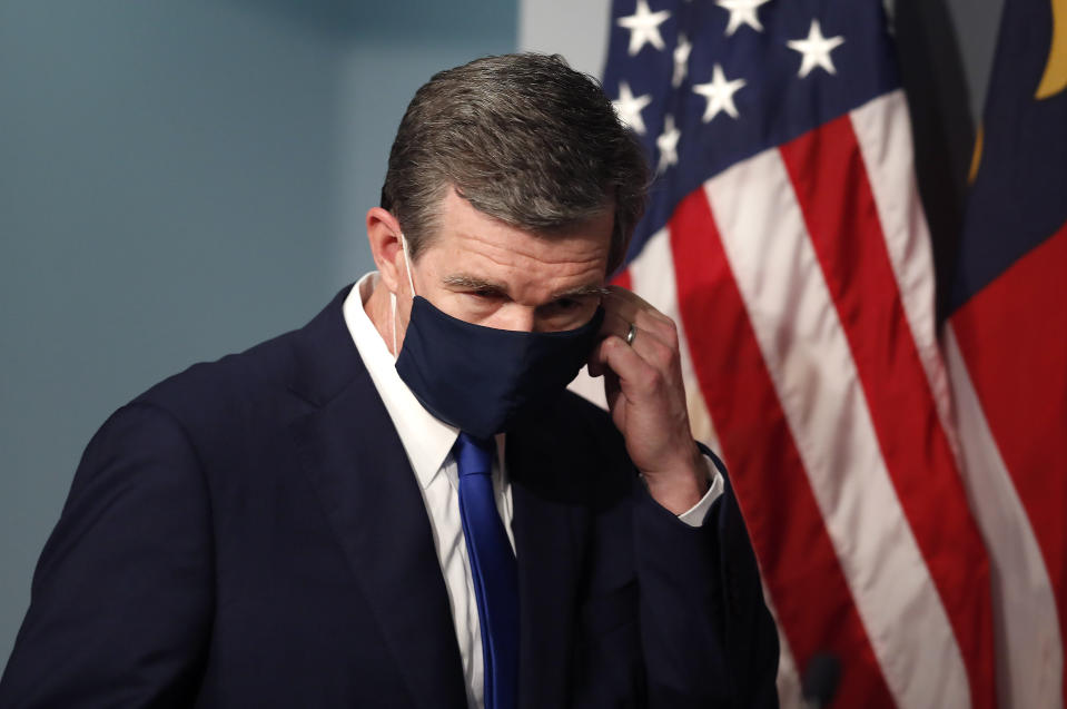 Gov. Roy Cooper prepares to take off his mask before speaking during a briefing at the Emergency Operations Center in Raleigh, N.C., Thursday, July 9, 2020. (Ethan Hyman/The News & Observer via AP)