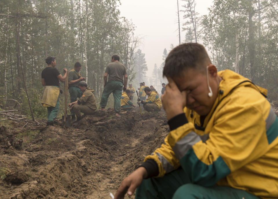 FILE - In this Sunday, July 18, 2021 file photo, employees of the Yakutlesresurs rest as they dig a moat to stop a forest fire outside Magaras village 87 km. (61 miles) west of Yakustk, the capital of the republic of Sakha also known as Yakutia, Russia Far East. Each year, thousands of wildfires engulf wide swathes of Russia, destroying forests and shrouding broad territories in acrid smoke. This summer has seen particularly massive fires in Yakutia in northeastern Siberia following unprecedented heat. (AP Photo/Alexey Vasilyev, File)