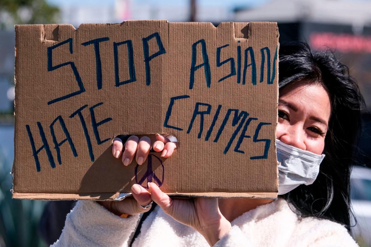 A demonstrator wearing a face mask and holding a sign takes part in a rally to raise awareness of anti-Asian violence, near Chinatown in Los Angeles, California, on February 20, 2021.