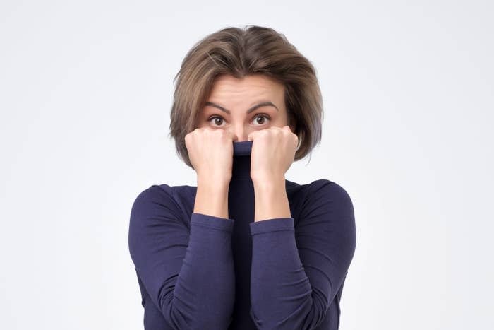 Girl pulling her trendy sweater over head being shy