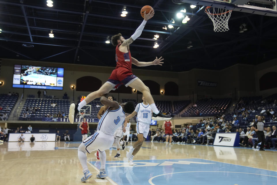 Saint Mary's guard Logan Johnson, above, leaps over San Diego guard Wayne McKinney III as he shoots during the first half of an NCAA college basketball game Thursday, Feb. 16, 2023, in San Diego. (AP Photo/Gregory Bull)