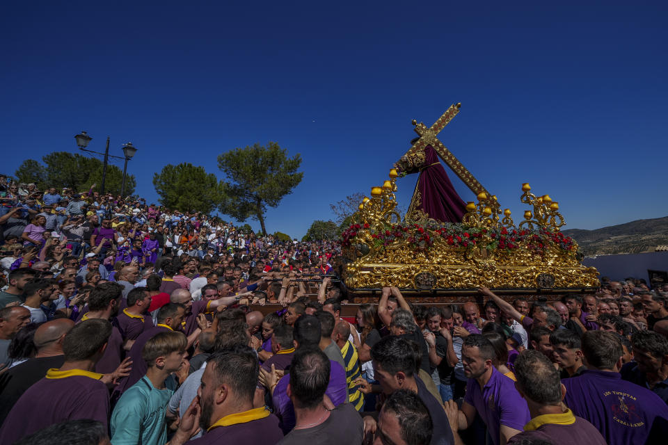 Penitentes de la hermandad de "Padre Jesús Nazareno" cargan un dosel con una estatua de Jesucristo con su cruz durante una procesión de Samana Santa en Priego de Córdoba, en el sur de España, el viernes 7 de abril de 2023. (AP Foto/Manu Fernandez)