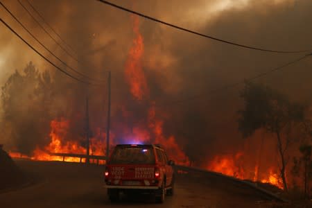 Firefighters drive through smoke from a forest fire in Chaveira