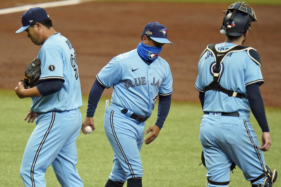 Toronto Blue Jays manager Charlie Montoya, center, takes the ball from starting pitcher Hyun-Jin Ryu, left, as he is taken out of the game against the Tampa Bay Rays during the second inning of Game 2 of an American League wild-card baseball series Wednesday, Sept. 30, 2020, in St. Petersburg, Fla. Looking on is catcher Danny Jansen. (AP Photo/Chris O'Meara)