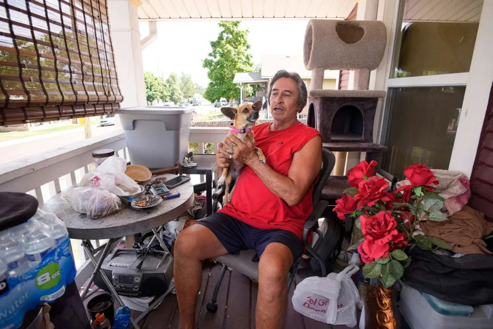 PHOTO: Ben Gallegos sits on the porch of his family's home with his dog as the daytime high temperature soars toward triple digits, July 27, 2023, in north Denver. (David Zalubowski/AP)