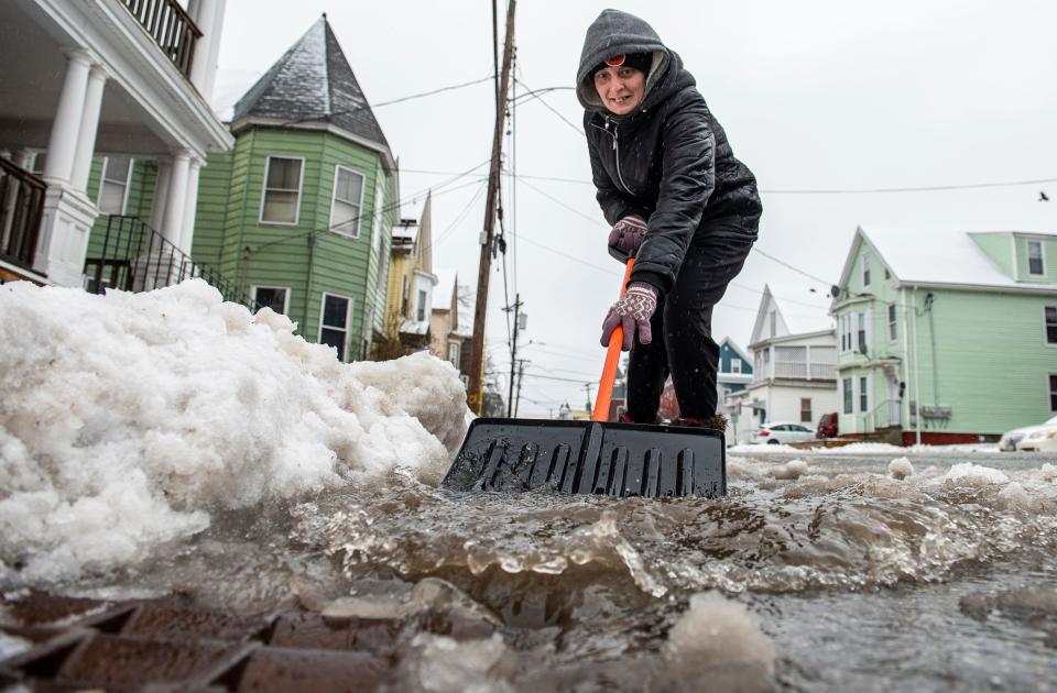 Amber Vallee pushes water down Walnut Street in Lewiston, Maine, Saturday morning, Jan 13, 2024, after snow turned to rain during yet another storm of mixed precipitation hit the area. "I wish it was all snow. I'm tired of this slush that will turn into ice at the bottom of our driveway." she said while keeping a path open for the rain and melting snow to flow into a nearby storm drain. (Russ Dillingham/Sun Journal via AP) ORG XMIT: MELEE101