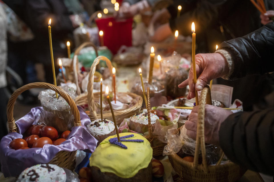 A man lights a candle during the during the cake and Easter egg blessing ceremony at the Orthodox Church of the Holy Spirit in Vilnius, Lithuania, Saturday, April 15, 2023. Orthodox Christians around the world celebrate Easter on Sunday, April 16. (AP Photo/Mindaugas Kulbis)