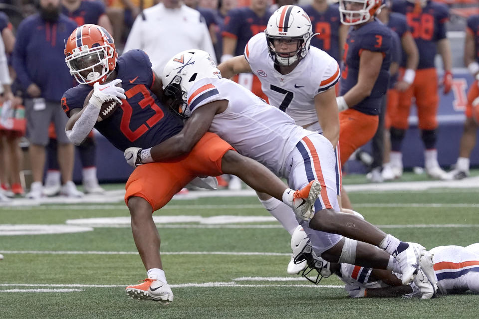 Illinois running back Reggie Love III carries the ball and is tackled by Virginia's Nick Jackson during the second half of an NCAA college football game Saturday, Sept. 10, 2022, in Champaign, Ill. Illinois won 24-3. (AP Photo/Charles Rex Arbogast)
