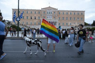 A dog makes its way as a participant raises a rainbow flag in front of the parliament during the annual Pride parade, in Athens, Saturday, June 10, 2023. June marks the beginning of Pride month in the U.S. and many parts of the world, a season intended to celebrate the lives and experiences of LGBTQ+ communities and to protest against attacks on hard-won civil rights gains. (AP Photo/Yorgos Karahalis)