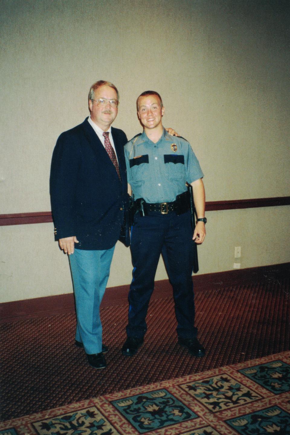 In this May 1998 family photo, Chris Mann, right, now the Democratic nominee for Kansas attorney general, stands with his father, left, in his new Lawrence police uniform, in Lawrence, Kansas. Mann would later be injured on duty and forced to give up his career as an officer before becoming a lawyer, a prosecutor in Kansas City, Kansas, and a national board member for Mothers Against Drunk Driving. (Chris Mann via AP)