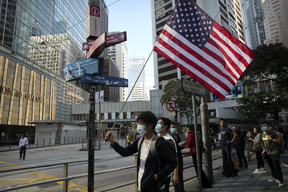 A protester holds an American flag during a demonstration in the financial district in Hong Kong, Wednesday, Nov. 20, 2019. Hong Kong schools reopened Wednesday after a six-day shutdown but students and commuters faced transit disruptions as the last protesters remained holed up on a university campus. (AP Photo/Kin Cheung)