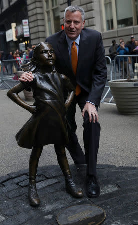 New York City Mayor Bill de Blasio poses next to the "Fearless Girl" statue in New York, U.S., March 27, 2017. REUTERS/Shannon Stapleton