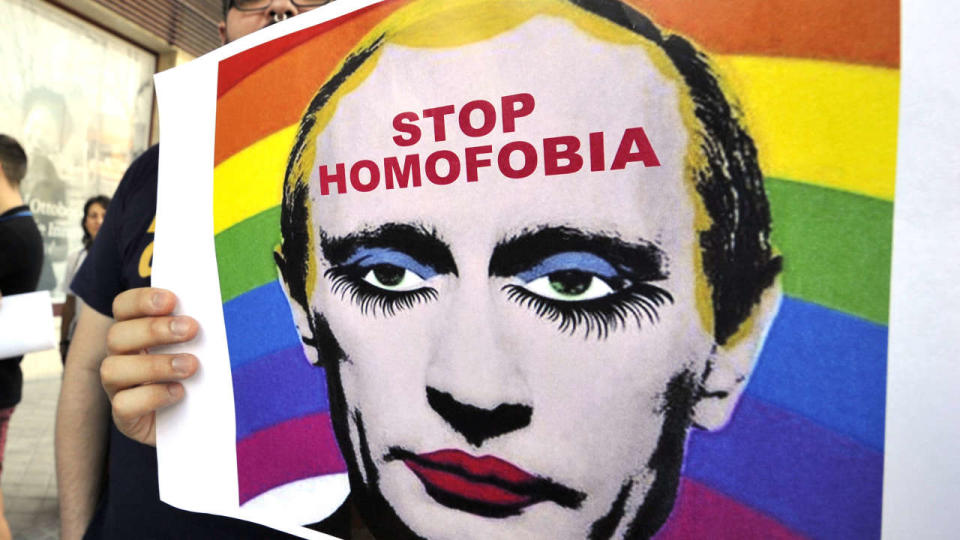 Un manifestant tient une affiche représentant le président russe Vladimir Poutine maquillé alors qu’il proteste contre l’homophobie et la répression contre les gays en Russie, devant l’ambassade de Russie à Madrid, le 23 août 2013.   (AFP PHOTO/ GERARD JULIEN (Photo de GERARD JULIEN / AFP)