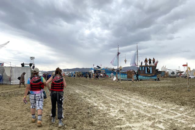 <p>Julie Jammot/AFP via Getty</p> Attendees at this year's Burning Man festival walk through mud in the desert