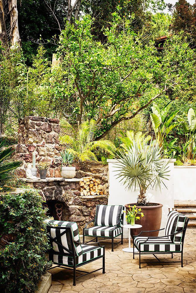 a couple of chairs in front of a fireplace with plants and a fire