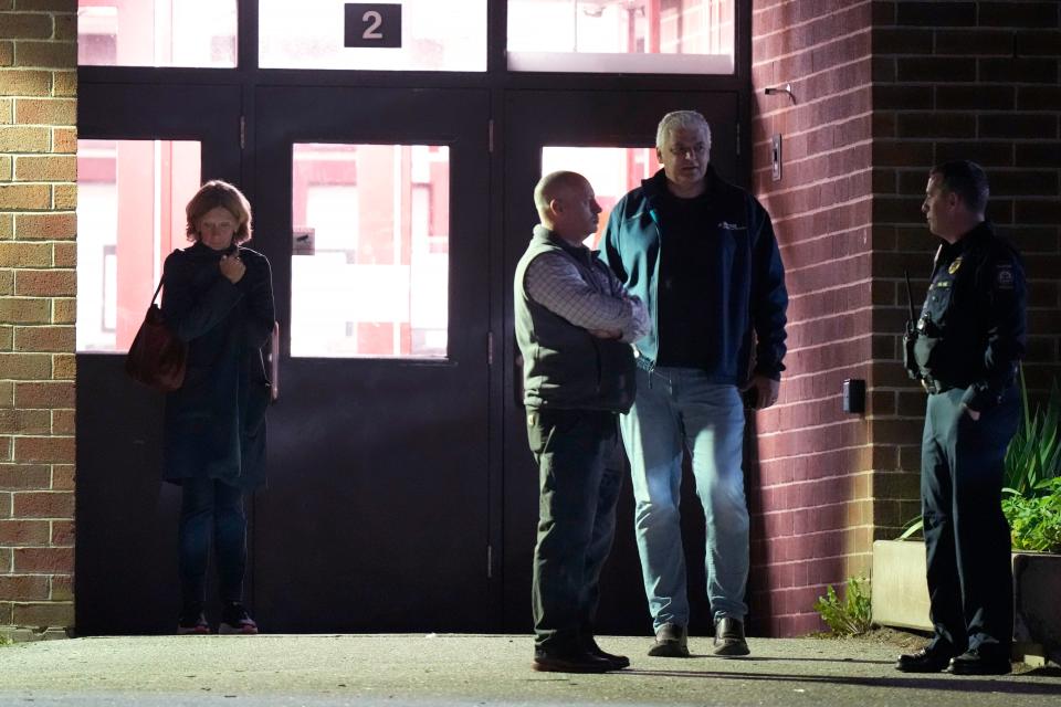 People stand outside a reunification center early Thursday, Oct. 26, 2023, at Auburn Middle School in Auburn, Maine, after shootings Wednesday at a bar and a bowling alley in Lewiston, Maine. (AP Photo/Steven Senne)