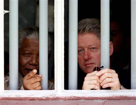 U.S. President Bill Clinton and South African President Nelson Mandela (L) peer through the bars of the cell in which Mandela spent 17 years while incarcerated by the former South African government, on Robben Island, in this file picture taken March 27, 1998. REUTERS/Stringer/Files