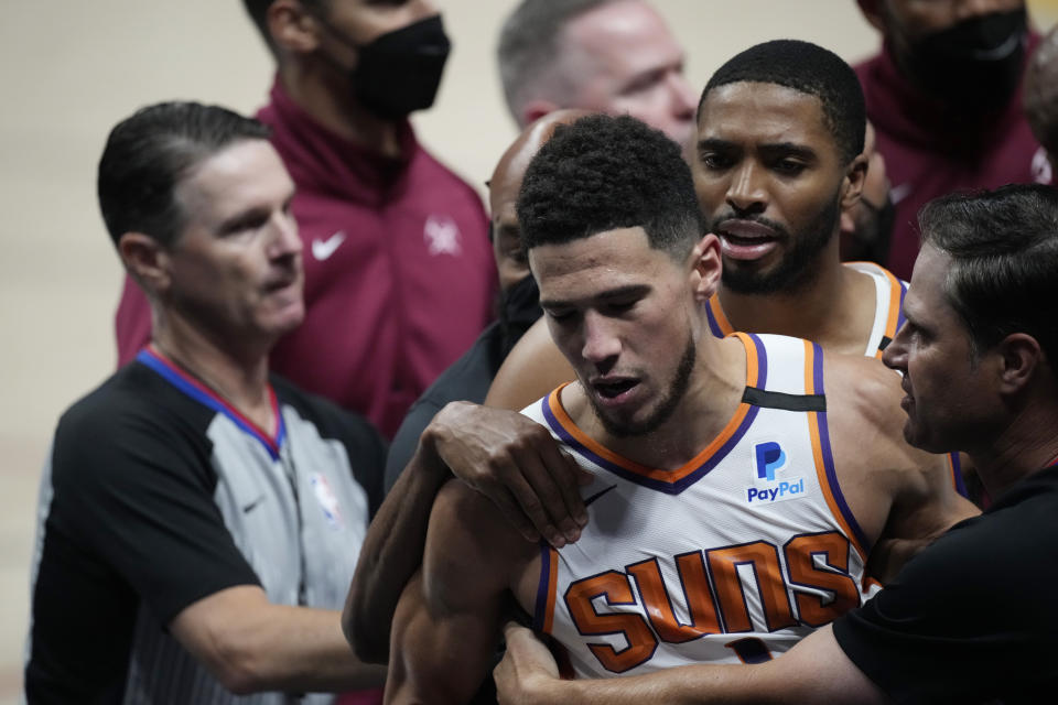 Phoenix Suns guard Devin Booker is restrained after getting into an argument with Denver Nuggets center Nikola Jokic in the second half of Game 4 of an NBA second-round playoff series Sunday, June 13, 2021, in Denver. (AP Photo/David Zalubowski)