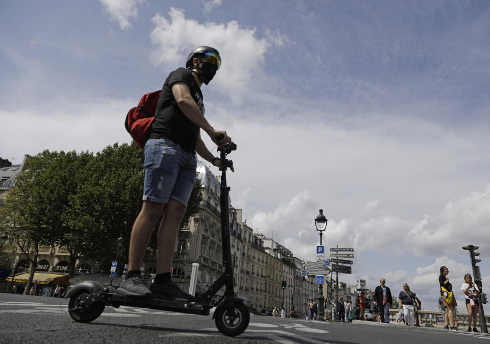 A man rides an electric scooter in Paris, Monday, Aug. 12, 2019. The French government is meeting with people who've been injured by electric scooters as it readies restrictions on vehicles that are transforming the Paris cityscape. The Transport Ministry says Monday's closed-door meeting is part of consultations aimed at limiting scooter speeds and where users can ride and park them. (AP Photo/Lewis Joly)