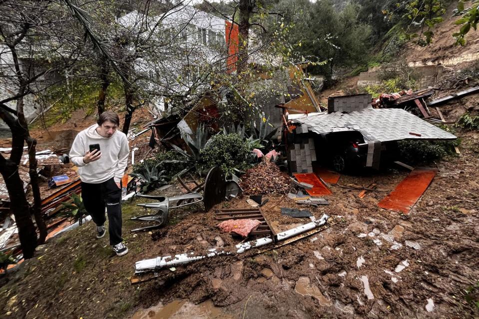 Storm chaser Tanner Charles walks by what is left of a home destroyed by a mudslide in the Beverly Crest area of Los Angeles.