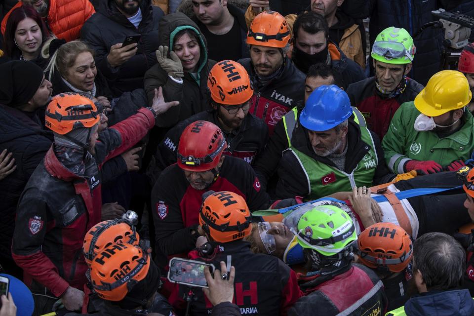 Raziye Kilinc is carried through a crowd on a stretcher after she was rescued under a destroyed building as her daughter, center, with the green black hood, waves in Iskenderun, southeastern Turkey, Friday, Feb. 10, 2023. A married couple was pulled from beneath the rubble of a collapsed building in Iskenderun after spending 109 hours buried within a small crevice. (AP Photo/Petros Giannakouris)