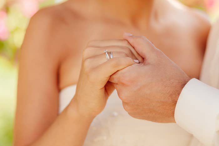 Close-up of a couple holding hands in wedding attire