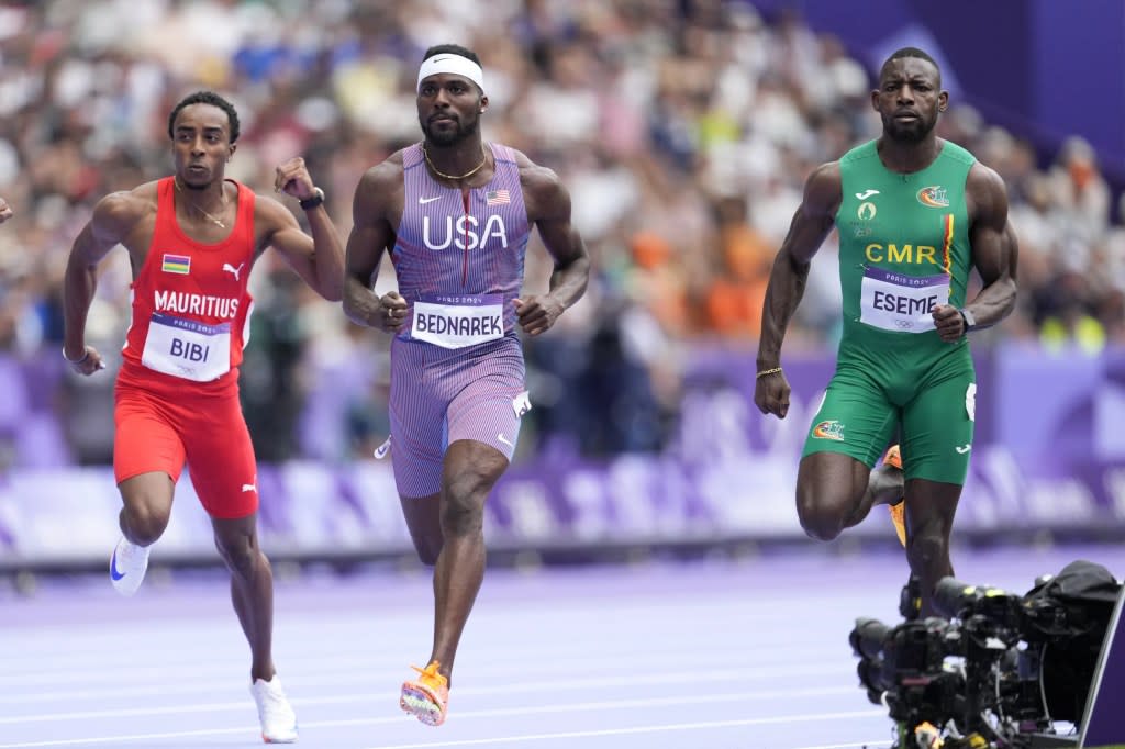 Kenneth Bednarek, of the United States, and Emmanuel Eseme, of Cameroon, run to qualify in a men’s 100 meters round 1 heat at the 2024 Summer Olympics, Saturday, Aug. 3, 2024, in Saint-Denis, France. (AP Photo/Ashley Landis)