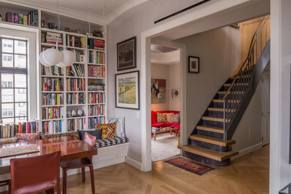 The banquette at the dining table is covered with a custom Suki Cheema textile. Peeking out from the adjacent room is a bright red Ligne Roset couch.